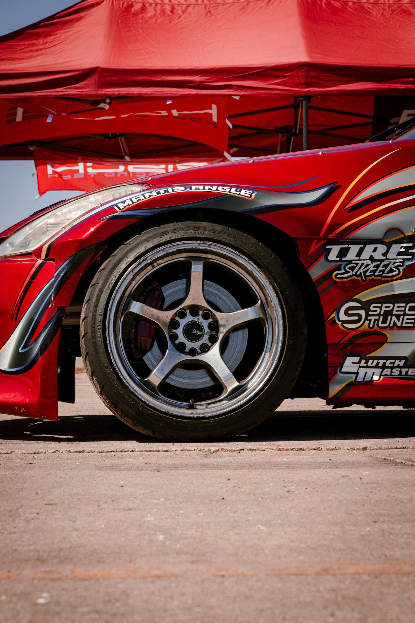Detailed view of a red race car wheel with vibrant decals under a canopy.